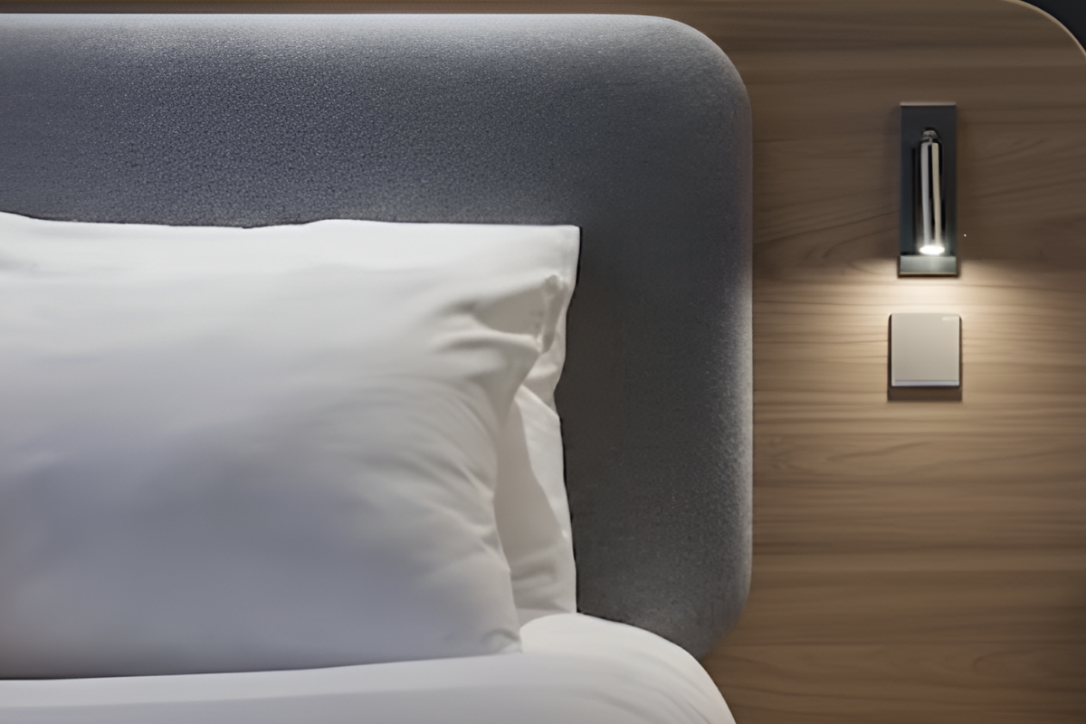 Goldberg Home bedside wall sconce with switch beside a luxury grey upholstered bed in a Singapore condo bedroom